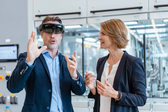 Businessman with AR glasses and businesswoman in a modern factory