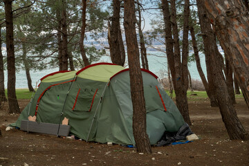 &laquo;Green camping tent amid pine trees near water