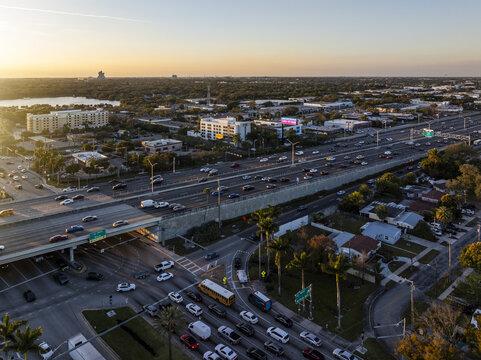 Aerial view of the I-95 highway cutting through the urban landscape, with the sun casting long shadows over the buildings and trees, Hollywood, Florida, United States.