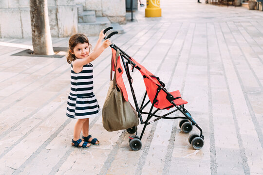 Portrait of smiling little girl pushing her stroller