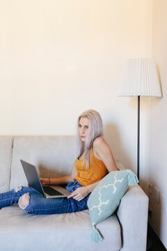 Young woman with laptop on couch at home