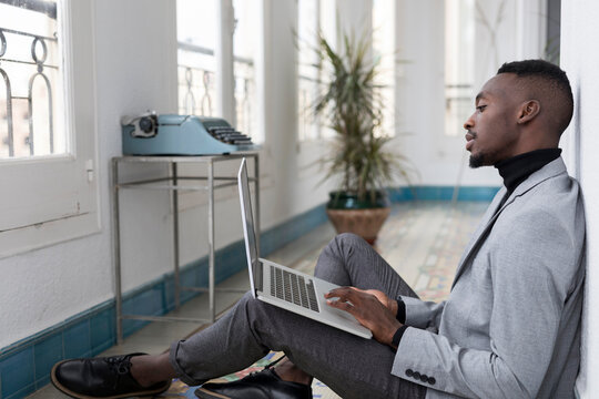 Young businessman sitting on floor in the office working on laptop