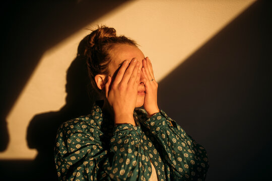 Young woman covering her eyes in sunshine