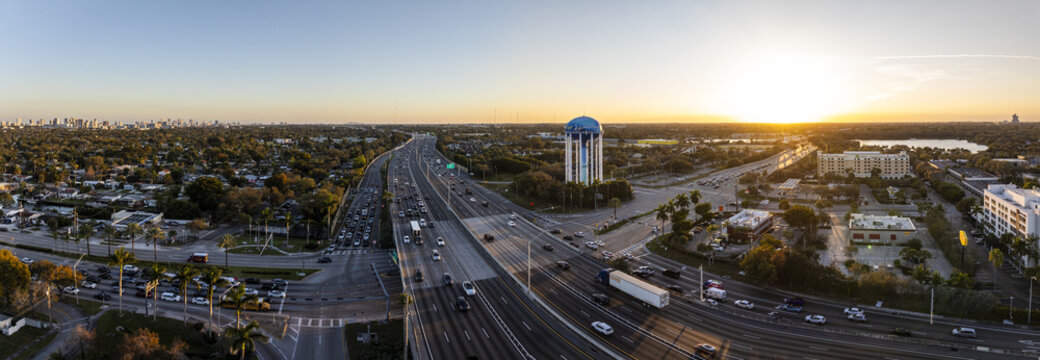 Aerial view of the vibrant city where the sun kisses the horizon, illuminating the water tower and the bustling highway, Hollywood, Florida, United States.