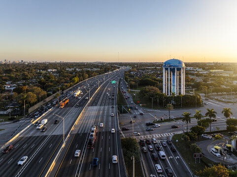 Aerial view of the iconic water tower standing tall amidst the bustling traffic and lush greenery under the golden light of the setting sun, Hollywood, Florida, United States.