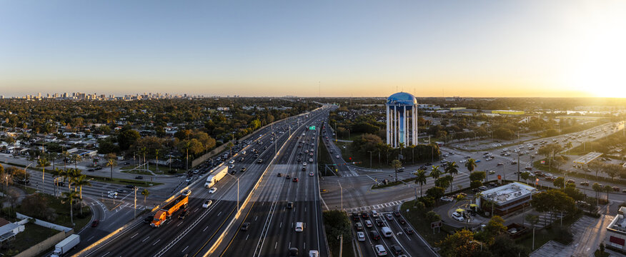 Aerial view of the vibrant highway stretches towards the horizon, with a water tower standing tall against the warm glow of the setting sun, Hollywood, Florida, United States.
