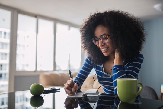 Smiling young woman taking notes at home