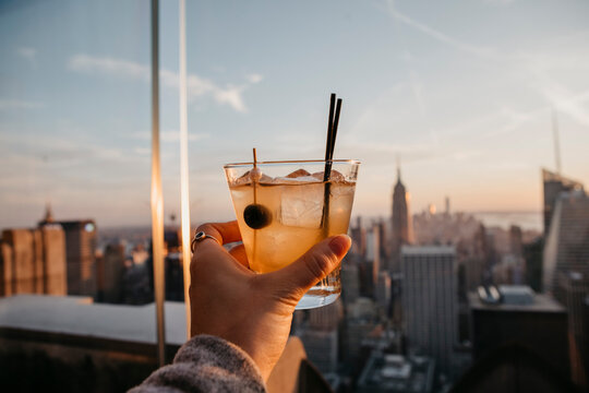 USA, New York, New York City, hand with cocktail glass at sunrise
