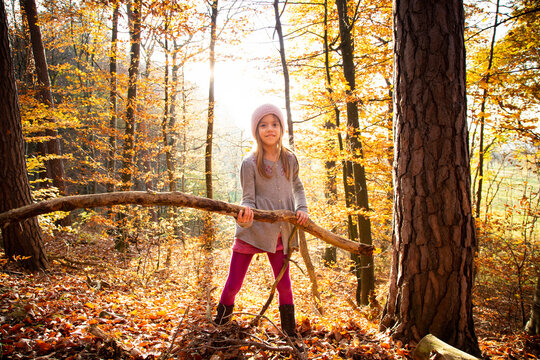 Young girl holding branch in autumn forest