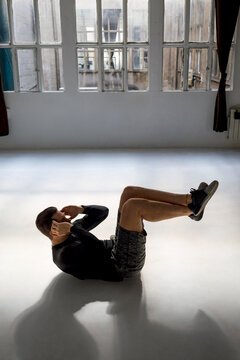 Athlete doing crunshes in sunlit studio