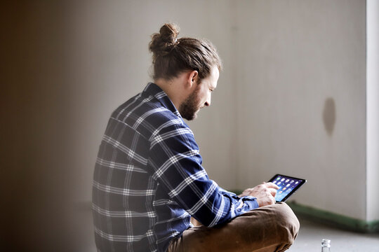 Worker on a construction site sitting on the floor using tablet