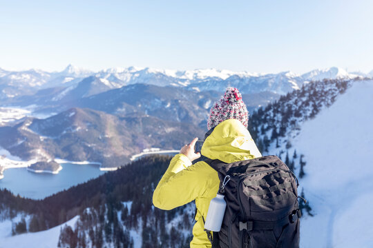 Germany, Bavaria, Alps, hiker with backpack at Lake Walchen taking smartphone picture