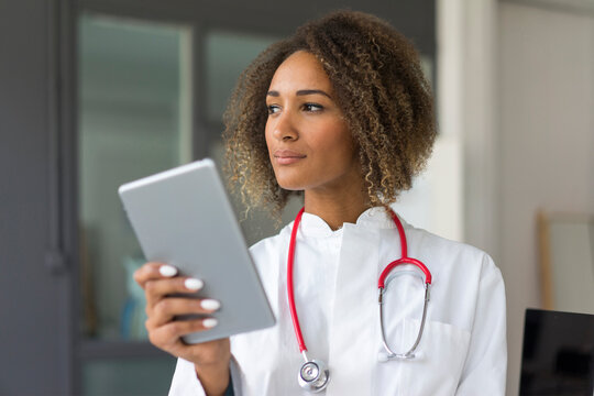 Portrait of young doctor with stethoscope and digital tablet looking at distance