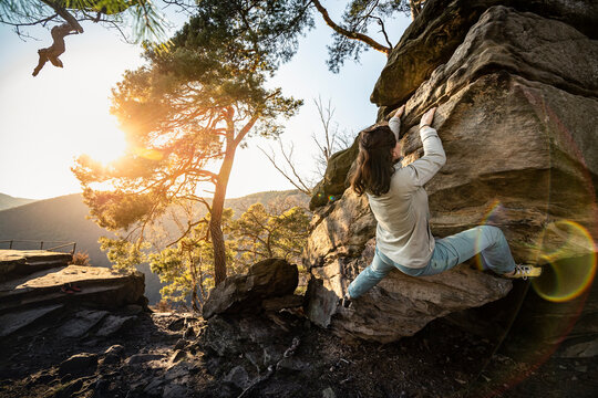 Female climber bouldering on sandstone boulder, Neustadt an der Weinstrasse, Rhineland-Palatinate, Germany