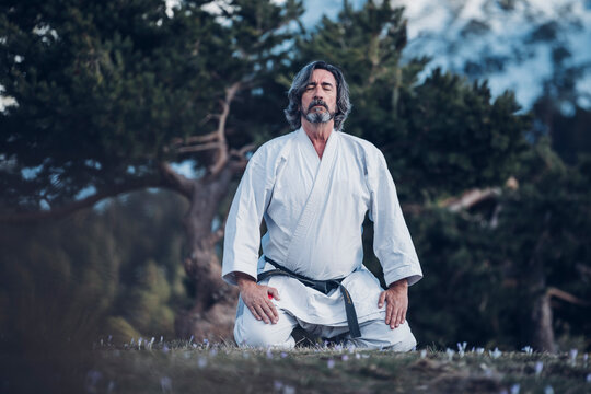 Senior man practicing karate outdoors, meditation