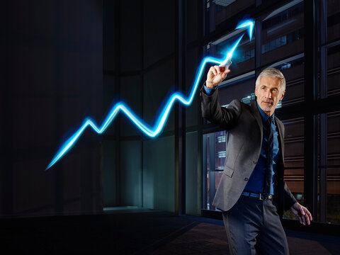 Businessman painting the stock market development with light