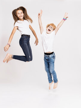 Cheerful siblings jumping against white background