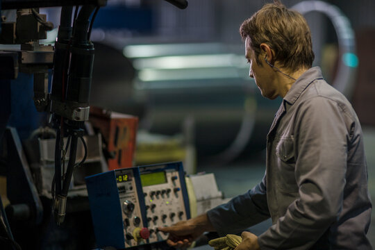 Worker operating machinery at control panel in factory