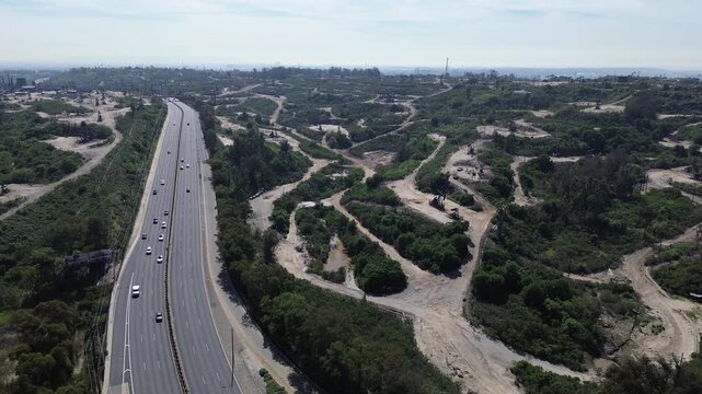 Pumpjacks and graded pads spread across Inglewood Oil Field near La Cienega Blvd, Kenneth Hahn State Recreation Area. Sunlit slopes, sparse shrubs, winding dirt roads rugged in Los Angeles, CA