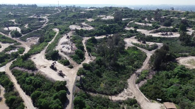Rolling hills with wells, pumpjacks and looping maintenance roads over Baldwin Hills open-space slopes, west of Kenneth Hahn State Recreation Area. Largest urban oil field in USA in Los Angeles