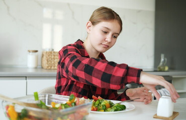 Teen Girl Salting Vegetable Salad At Home In The Kitchen