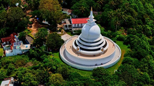Aerial view of the Japanese Peace Pagoda at Rumassala, a white stupa surrounded by lush green forest on a hilltop