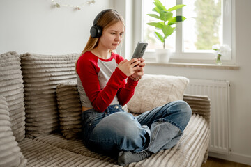 Teen Girl Sitting On The Couch With Headphones And Smartphone