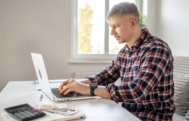 Man Working On Finances At Home With A Laptop
