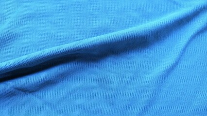 Blue sports jersey fabric texture close up. Soft football clothing textile background. Sports wear background with smooth blue fabric detail.