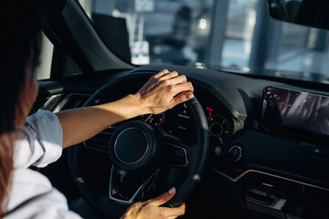 Fototapeta premium Hands are on the steering wheel. Detailed close up view of woman that is driving the new car