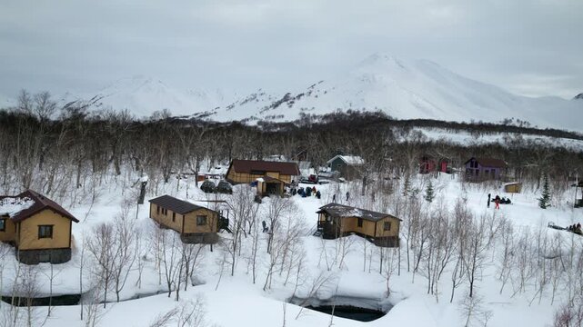 Snow covered coastal homes and shoreline under overcast winter sky, aerial overview of Kamchatka Russia outpost