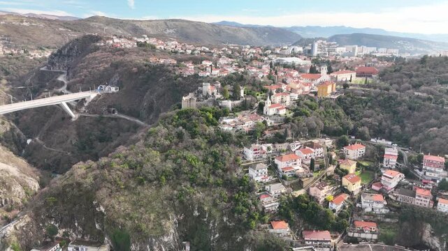 Drone approaches Trsat Hill and its settlement, with the road viaduct spanning the deep Rječina gorge on the left and Rijeka&rsquo;s urban landscape in the background.