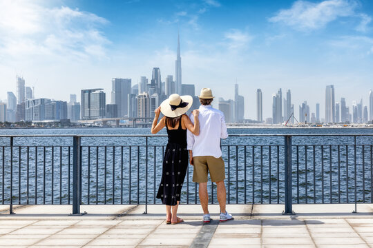 A beautiful tourist couple on a sightseeing trip enjoys the view of the skyline of Dubai, UAE, as a city travel concept