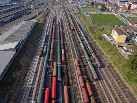 Aerial view of the extensive railway tracks converge, lined with colorful freight cars contrasting against the urban sprawl, Chiasso, Ticino, Switzerland.