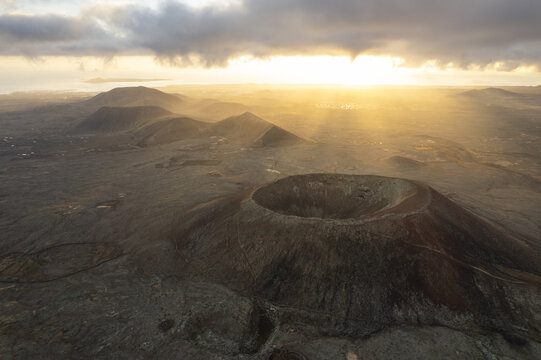 Aerial view of the Calderon Hondo crater basking in the warm glow of the setting sun, its rugged textures highlighted against the soft light, Fuerteventura, Canarias, Spain.