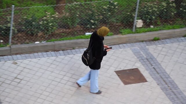 Musulmana isl&aacute;mica con pa&ntilde;uelo hiyab en cabeza de mujer mora usando tel&eacute;fono m&oacute;vil por la calle