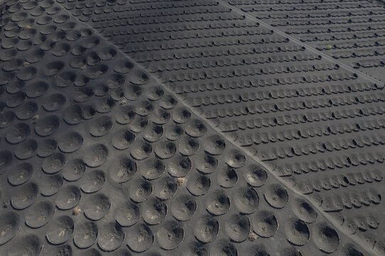 Aerial view of volcanic craters create a dramatic, textured landscape, the stark black soil contrasting with the geometric patterns, La Geria, Canarias, Spain.