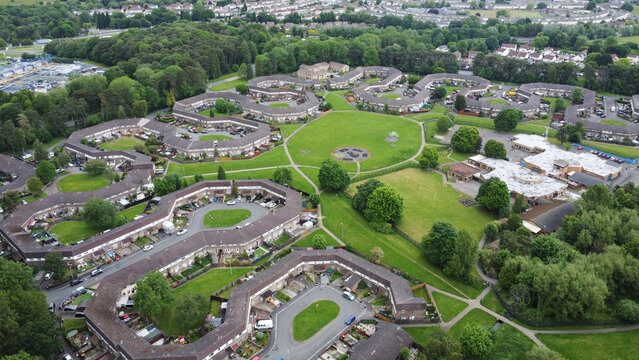 Aerial view of circular houses nestled among vibrant green spaces and tree lines, a tranquil residential community, Newport, Wales, United Kingdom.