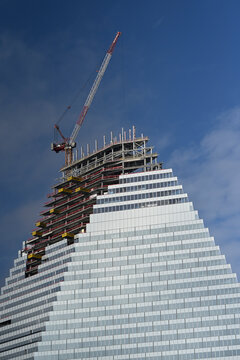 Workers are busy on the construction site of La tour Triangle at Porte de Versailles in Paris. The building features a unique triangular design and reflective glass.