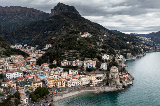 Aerial view of the vibrant town nestled against the dramatic cliffs, where the turquoise sea meets the colorful buildings under a moody sky, Cetara, Campania, Italy.