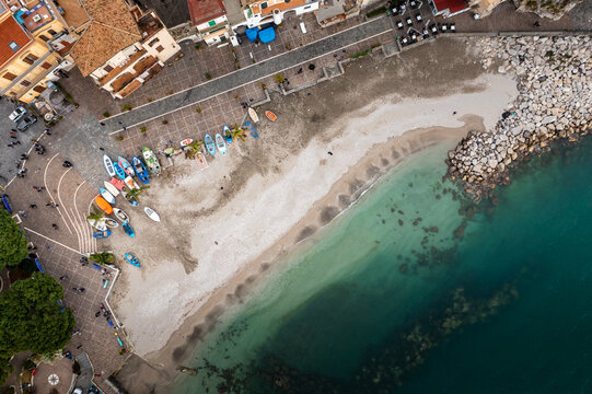 Aerial view of vibrant boats rest on the sandy shore where the town square meets the turquoise sea, a picturesque coastal scene., Cetara, Campania, Italy.