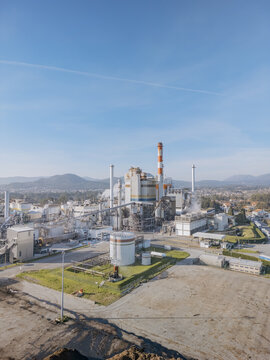 Aerial view of the DS Smith Paper mill industrial complex with towering structures, a red and white chimney piercing the sky, set against a backdrop of distant mountains, Deocriste, Portugal.