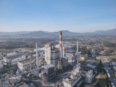 Aerial view of the DS Smith paper mill industrial complex with tall chimneys piercing the sky, contrasting with the distant mountains, Deocriste, Portugal.