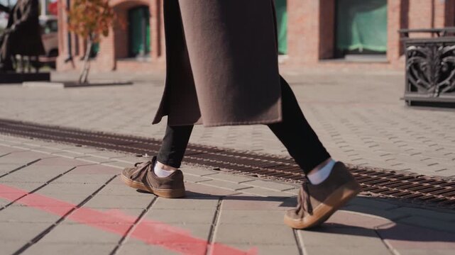 Woman stepping over red painted line, brown leather shoes pause near curious pigeon, playful hop and slight tilt of foot, sidewalk plaza with bench and brick facades bathed in warm sunlight, frames