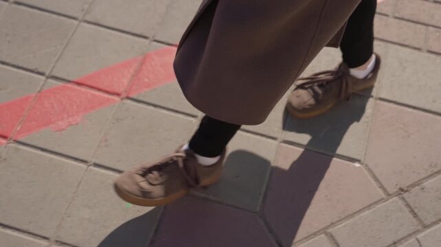 Brown shoes cautiously cross bright red boundary. Footwear carefully crosses striking red line amidst street environment. Brown shoes are delicately crossing vivid red boundary line in urban setting