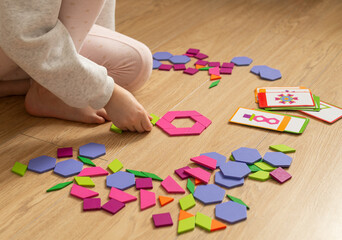 Preschool child learning geometry with colorful pattern blocks. STEM education concept, cognitive development, logical thinking and math skills training through hands-on Montessori activity at home. © marinasokolchik