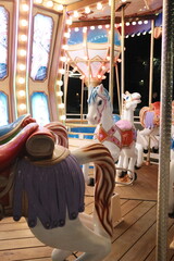 Colorful carousel horses shine under bright lights at night. © vannet