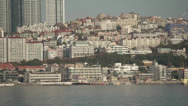 View of city skyline and cars of Haeundae Blueline Park in distance from Haeundae Beachon a sunny day, Busan, South Korea