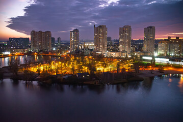 Naklejka premium Panoramic View of Kyiv Cityscape with Modern Residential Skyscrapers and River at Twilight