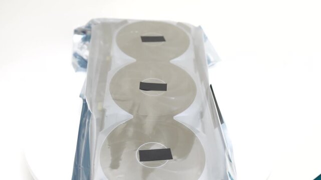 Graphics card GPU hardware showing a new triple fan component inside a protective anti static bag on white background